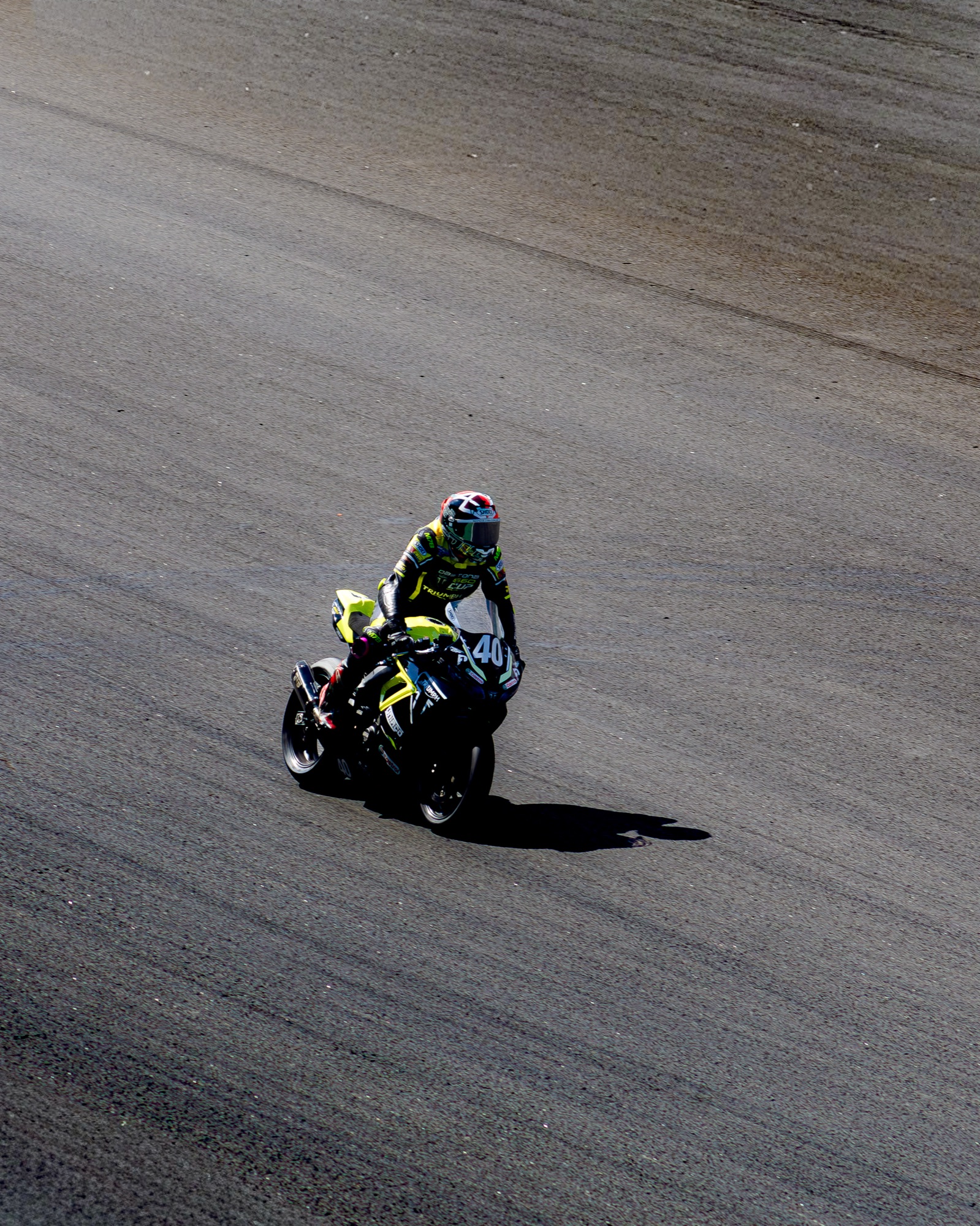 Piloto #40 da Triumph Daytona 660 Cup inclinado na curva, sombra longa no asfalto