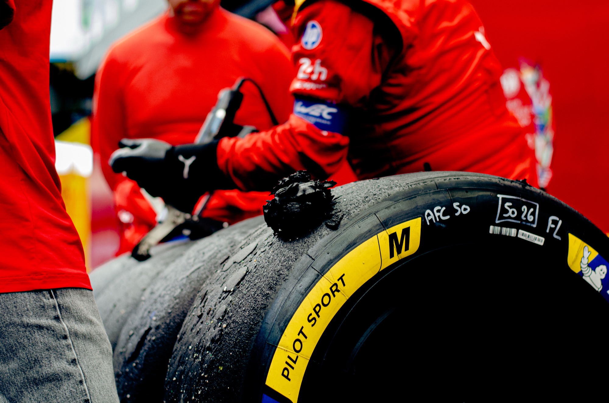 Mecânico da AF Corse com pneu Michelin já usado, marcado à mão "AFC 50", cheio de borracha grudada
