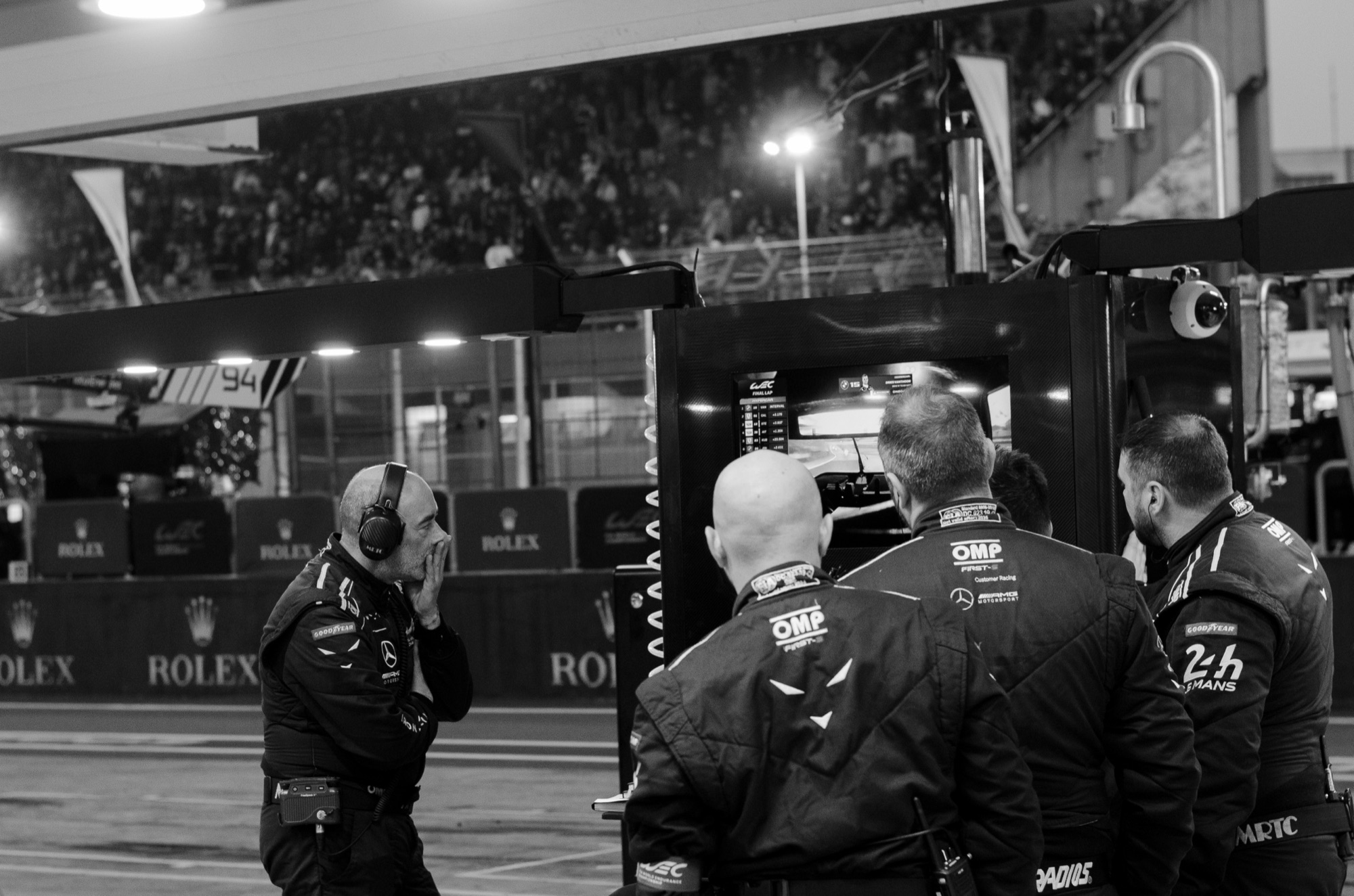 Muro dos boxes na volta final: a equipe da Iron Lynx em silêncio diante do monitor, em preto e branco