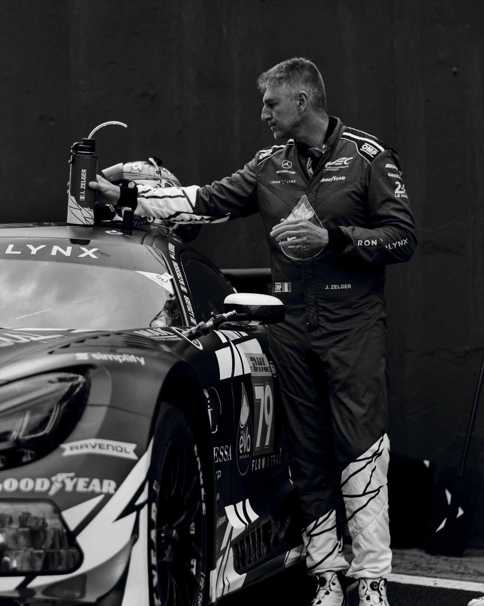 O piloto J. Zelger alcançando a garrafa sobre o teto do Mercedes-AMG GT3 #79, em preto e branco